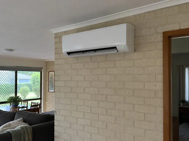 White split system mounted high on a brick internal wall in a tiled living room in Reedy Creek